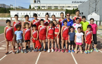 Integrantes de la escuela de atletismo con su entrenador, Chema Fernández, (de azul) en la pista de atletismo de Albolote