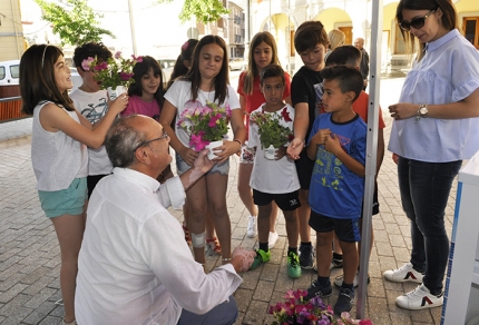 Escolares del CEIP Tínar reciben una planta tras visitar uno de los stand de la feria medioambiental