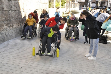 Varios escolares en sillas de ruedas sortean algunos obstáculos en un circuito urbano.