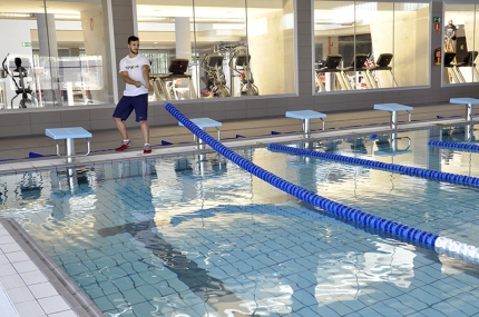 Un trabajador de BPXport coloca las corcheras en la piscina del CDU, que ya está totalmente llena y a punto, al fondo se aprecian las máquinas de cardio del gimnasio. . 