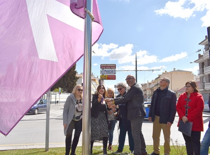 Izada de la bandera violeta con el lazo blanco, símbolo de la igualdad de género.