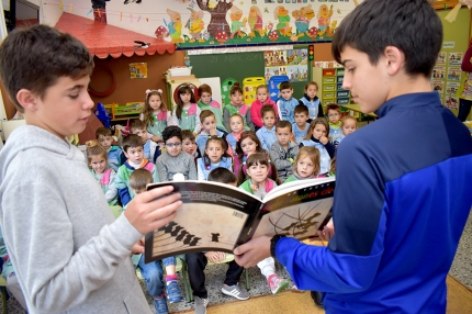 Alumnos del IES Aricel muestran un libro a los infantiles del cole Abadía. 