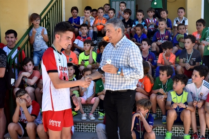El concejal de Deportes en funciones, Diego Valero, entrega un trofeo a un integrante de la escuela de fútbol en presencia del resto de deportistas. 