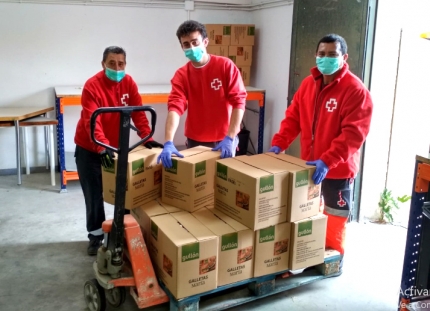 Voluntarios de Cruz Roja descargan un palé con productos de alimentación para su reparto