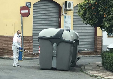 Un operario desinfecta un contenedor en una calle de Albolote.