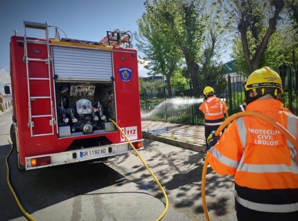 Varios efectivos de Protección Civil desinfecta la acera de una calle de Albolote.