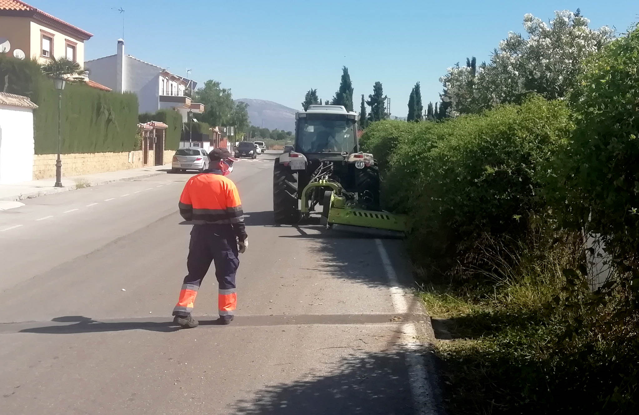 Un tractor con un brazo mecánico desbroza las cunetas del Camino de Albarrate en las urbanizaciones de la falda de la sierra