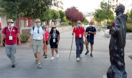 El grupo de peregrinos pasa junto la estatua del santo San Juan de la Cruz en la Avenida de la Constitución de Granada