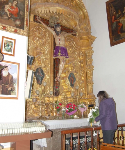 Una mujer acerca a la imagen del Cristo un ramo de flores en la tarde del martes 27 de enero.
