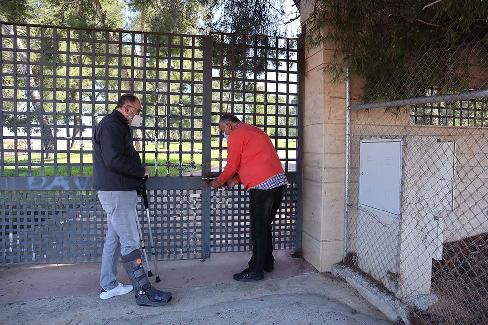 El concejal de El Chaparral y un operario abren la cancela de acceso al recinto de Los Pinos.