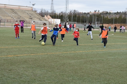 Un grupo de niños y niñas disputan un partido de fútbol en el campus deportivo 