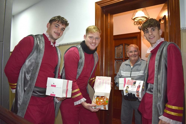 Pajes de los Reyes Magos entregan un roscón a un vecino de la localidad.