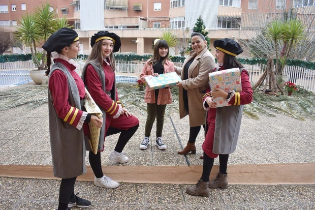 Los pajes del Ayuntamiento y la concejala de Festejos, Ingrid Pérez, entregan a Elvira de 10 años su juguete de Reyes. Abajo espectáculo navideño del pasado 2023.