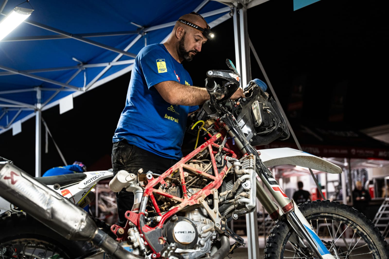 Juan Sánchez arreglando en el campamento una de los motos del Dakar