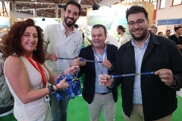 El concejal Juanjo Martínez, junto a representantes del Consorcio de la Vega y del Ayto. de Granada muestra la pulsera de Albolote alusiva al Camino de Santiago que se ha repartido entre los asistentes a la feria 