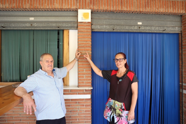 Carolina Suárez y su padre Paco, señalan el Solete Repsol que ya está colocado en la puerta del establecimiento